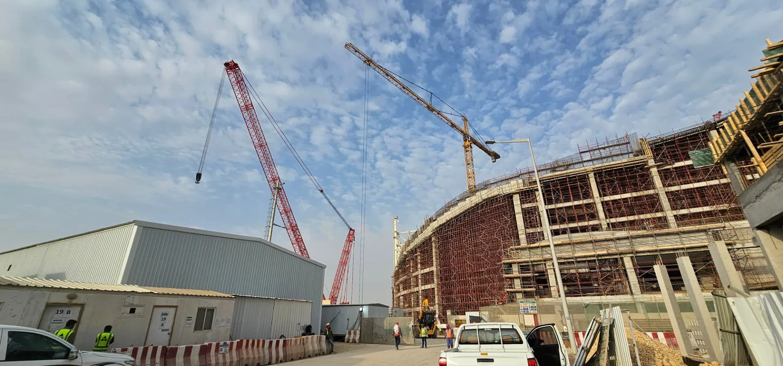 Active industrial construction site with tower and crawler cranes