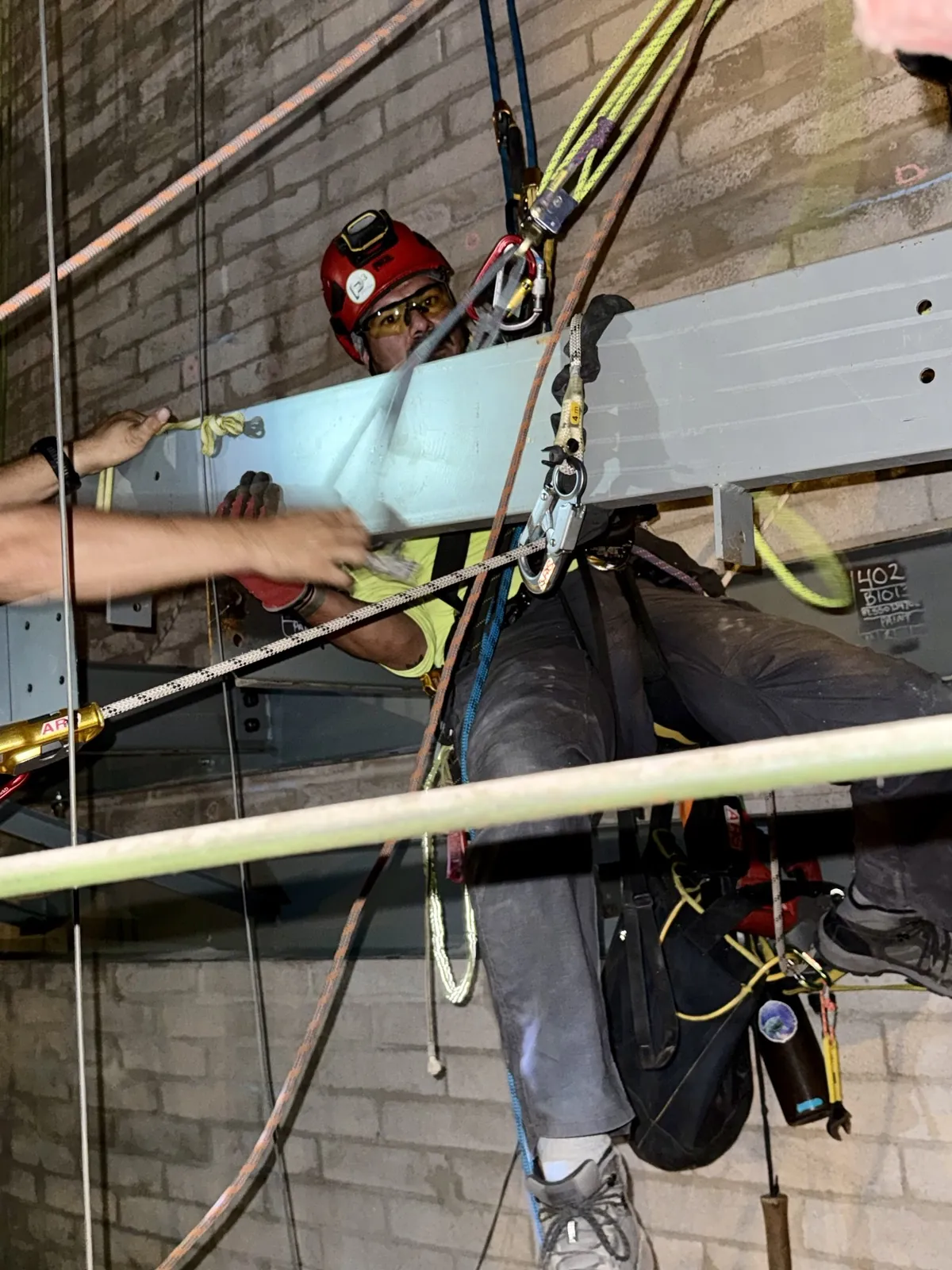 Rope access technician suspended on rope installing structural steel inside an industrial building