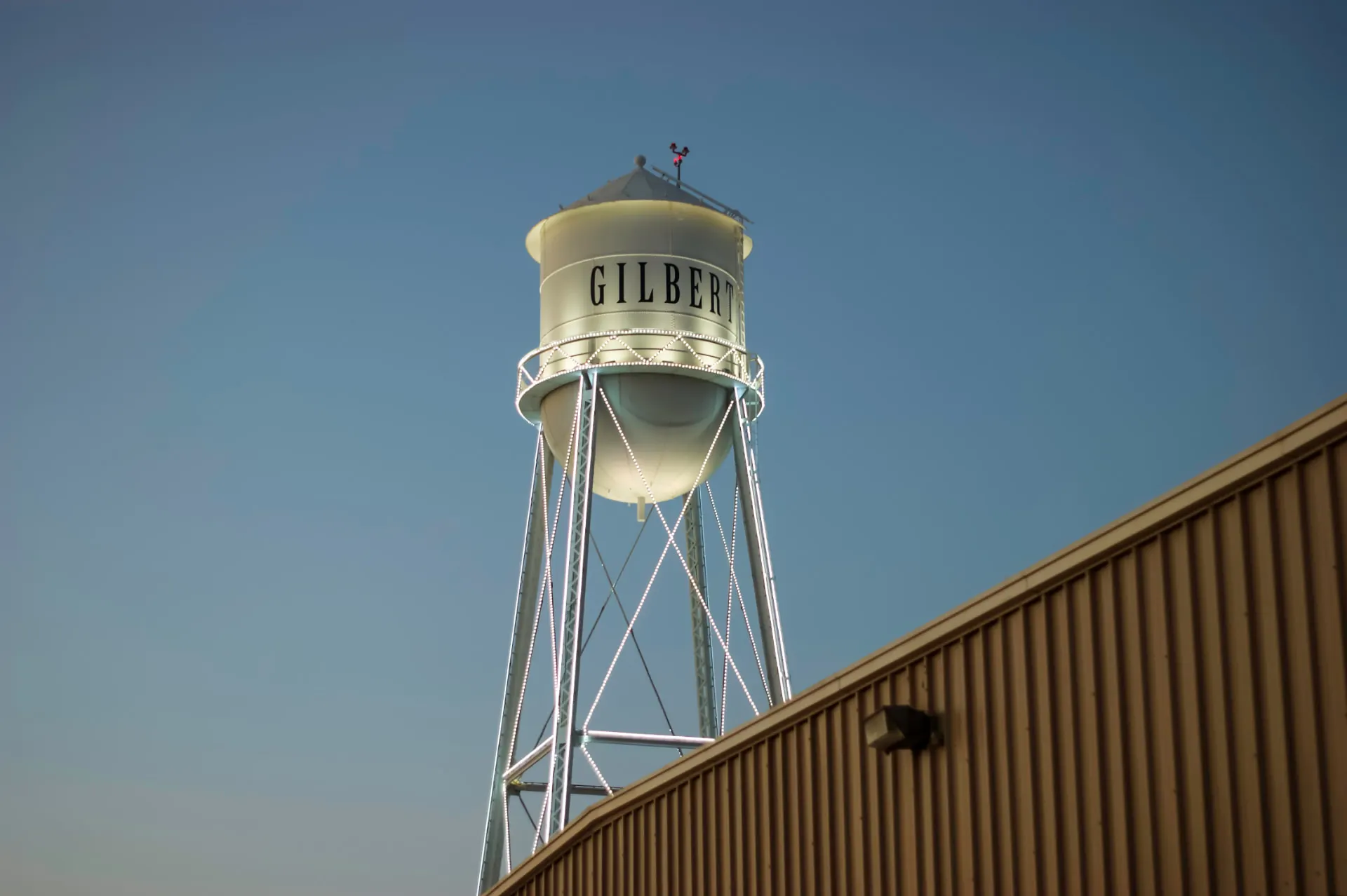 The Gilbert water tower rising above an industrial building at dusk