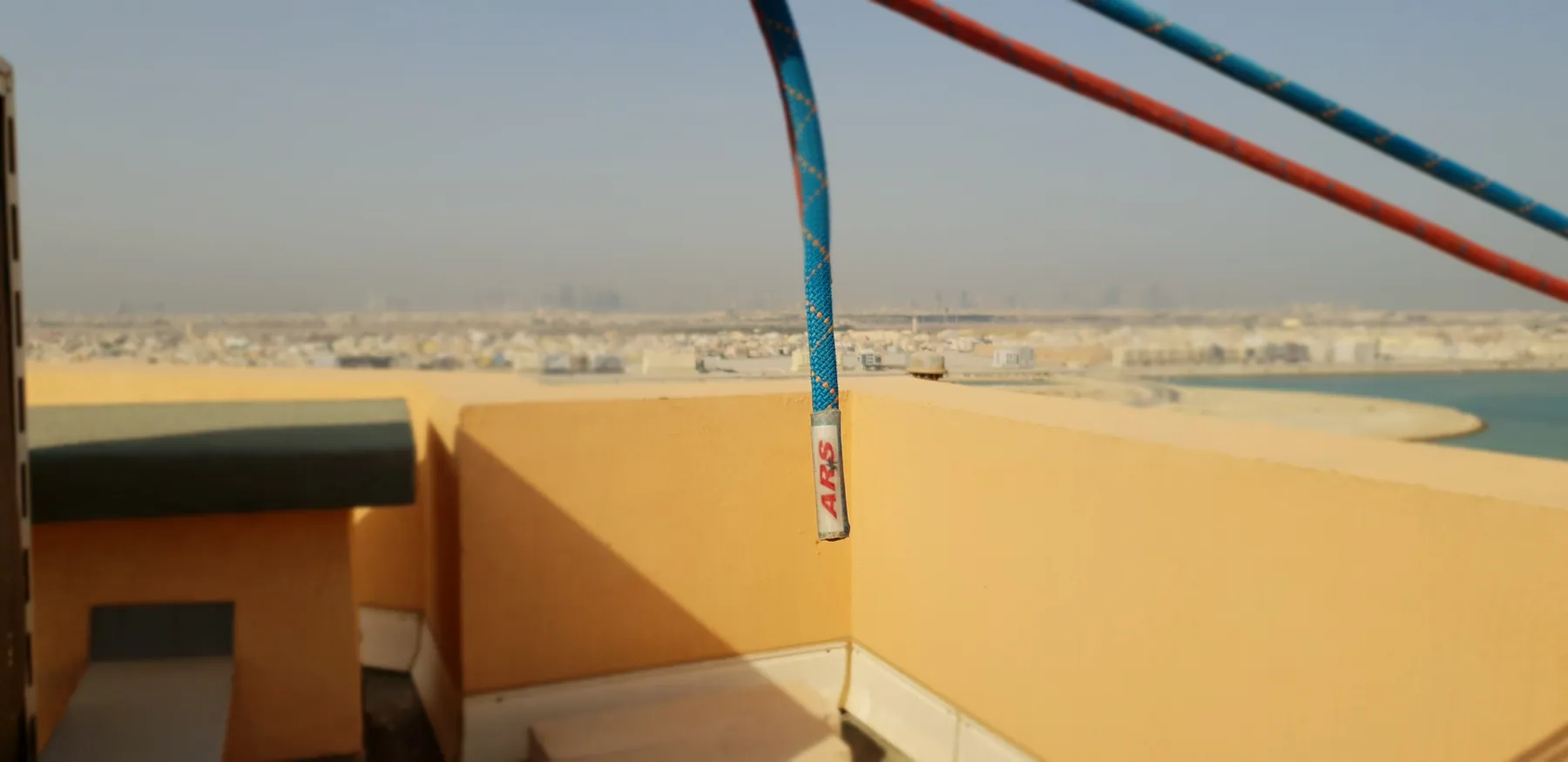 Rope lines running over a building parapet edge above open ground