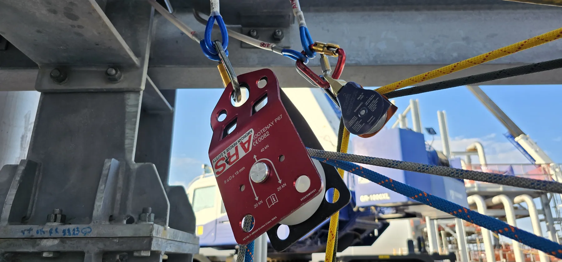 Red rigging pulley and carabiners anchored beneath a structural steel member