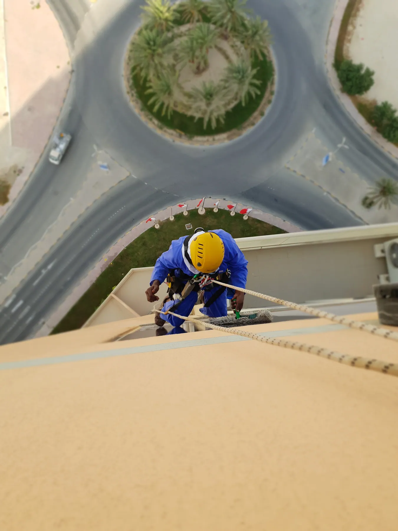 Overhead view looking down a building facade at a suspended rope access technician