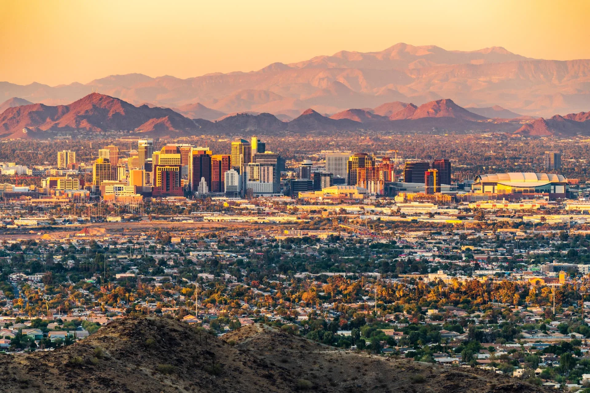 Downtown Phoenix skyline at sunset with surrounding desert mountains
