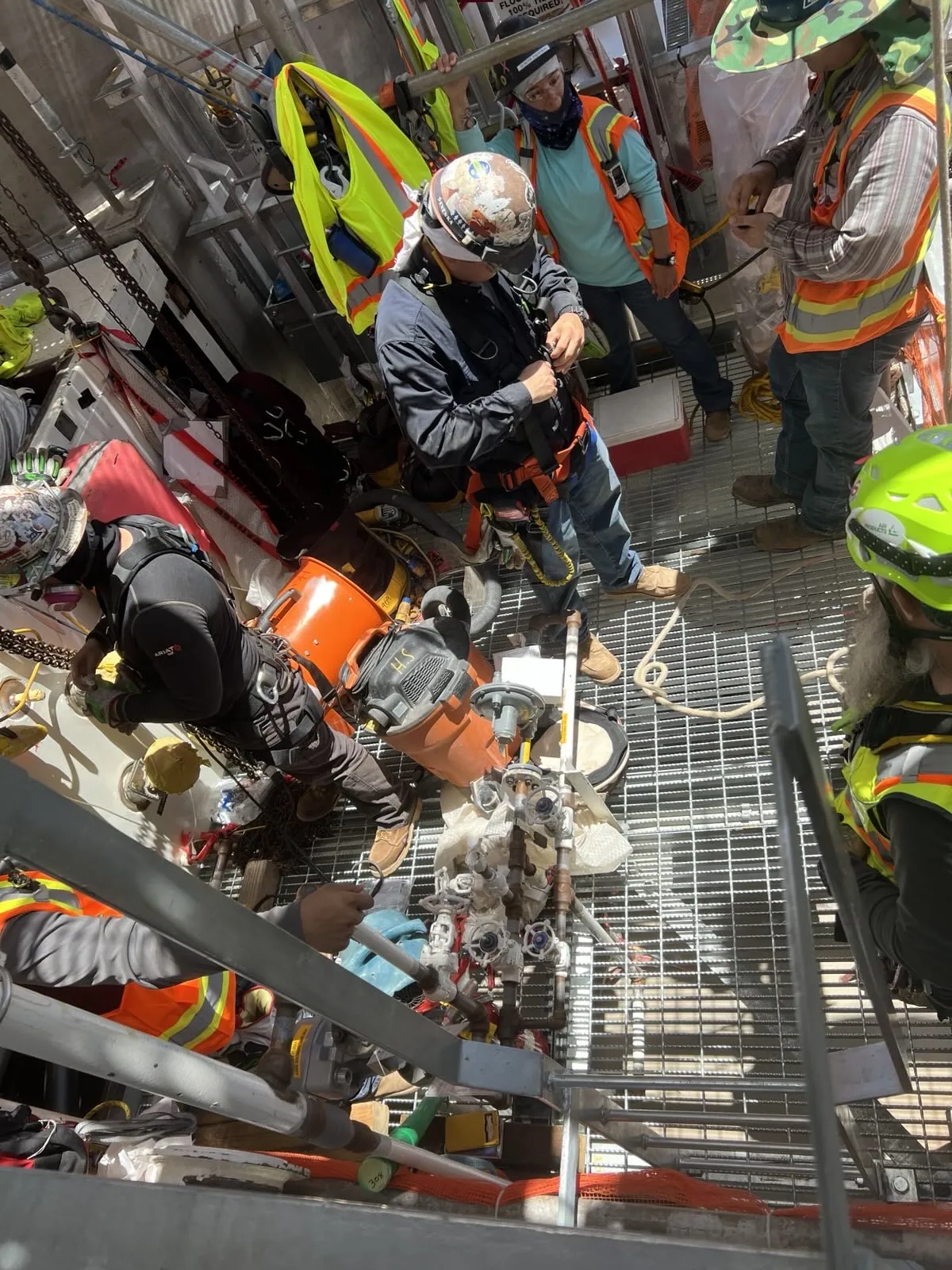 Crew in full PPE working with equipment on a congested industrial plant walkway