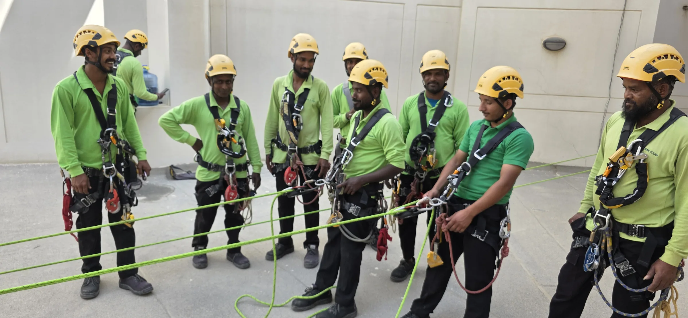 Harnessed rope-access trainees assembled beside their training systems