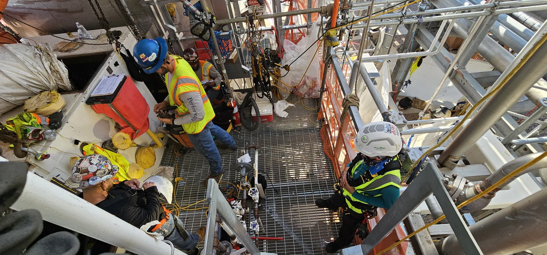Technicians working at height among pipework and steel structure inside an industrial plant