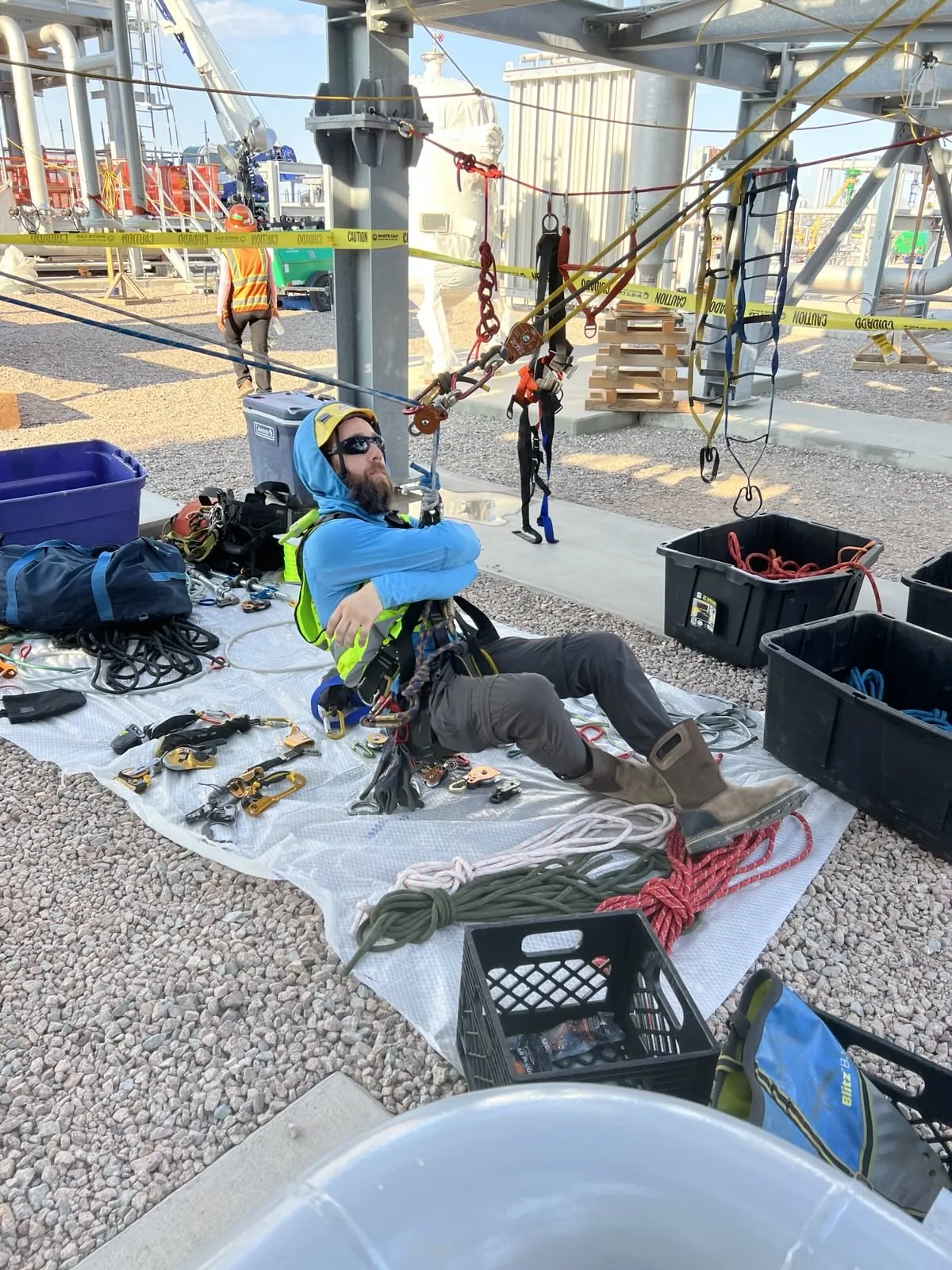 Technician preparing rescue and rope equipment laid out on a ground sheet at a plant site