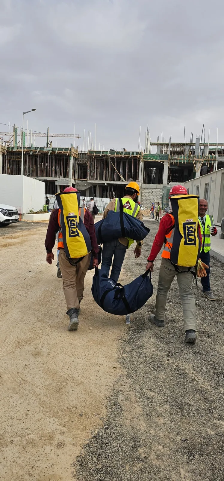 ARS rescue technicians transporting a casualty litter and rescue equipment across a job site
