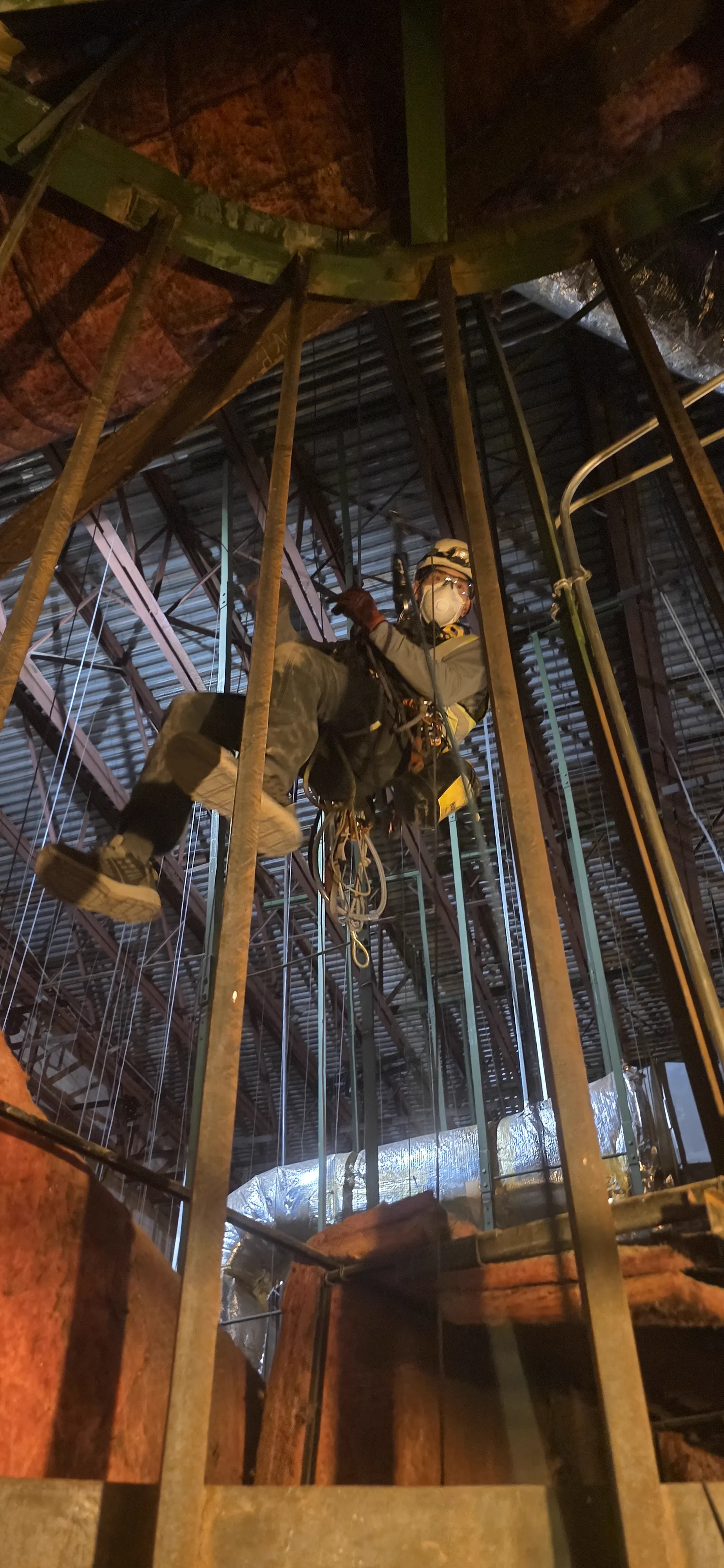 Overhead anchor rigging and rope lines set inside a vertical industrial shaft