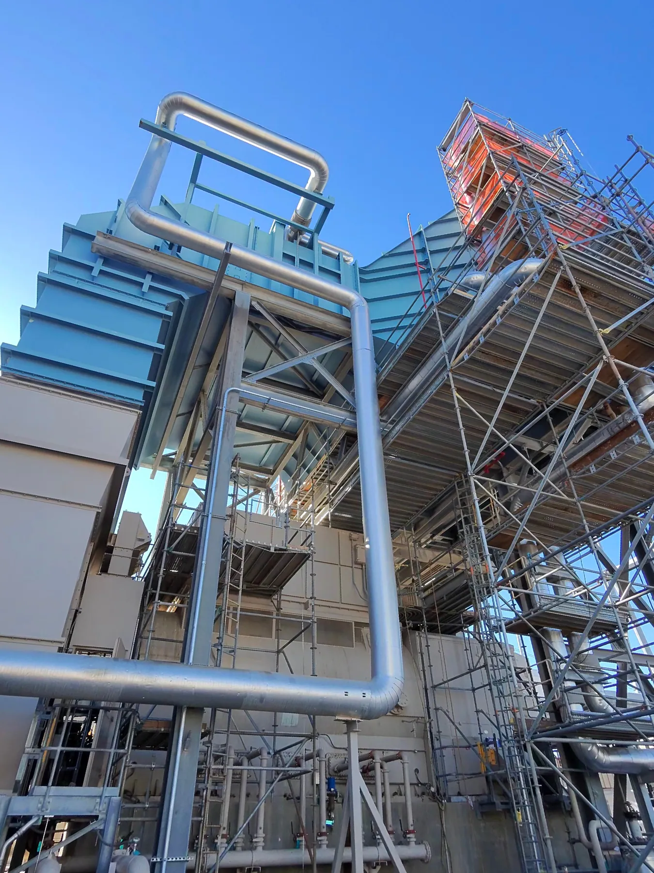 Scaffolded access structure and stair tower beside industrial plant equipment
