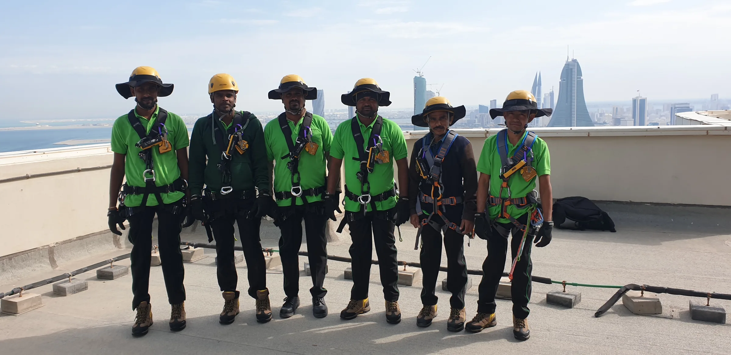 Six harnessed technicians assembled on a high-rise rooftop