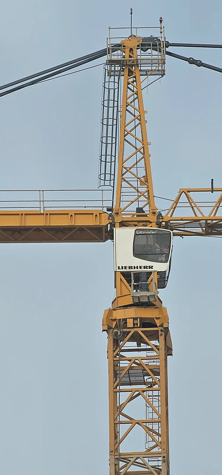 Tower crane head and operator cab viewed from ground level on a high-rise project