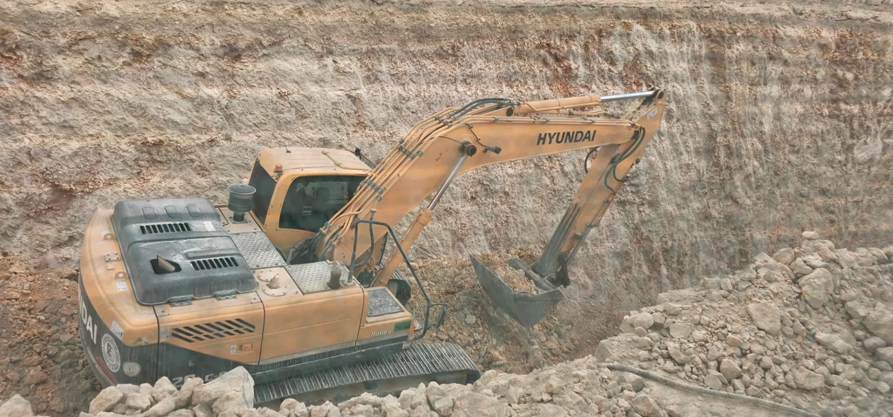 Excavator working at the base of a deep rock excavation face