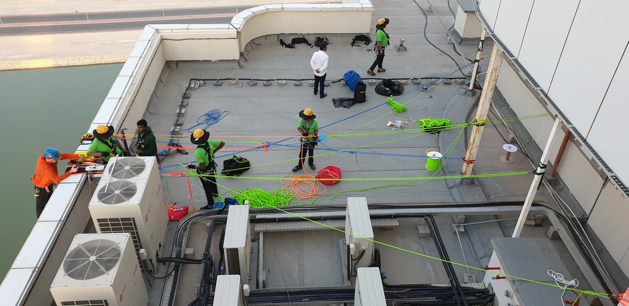 Overhead view of a crew coordinating multiple rope systems across a rooftop