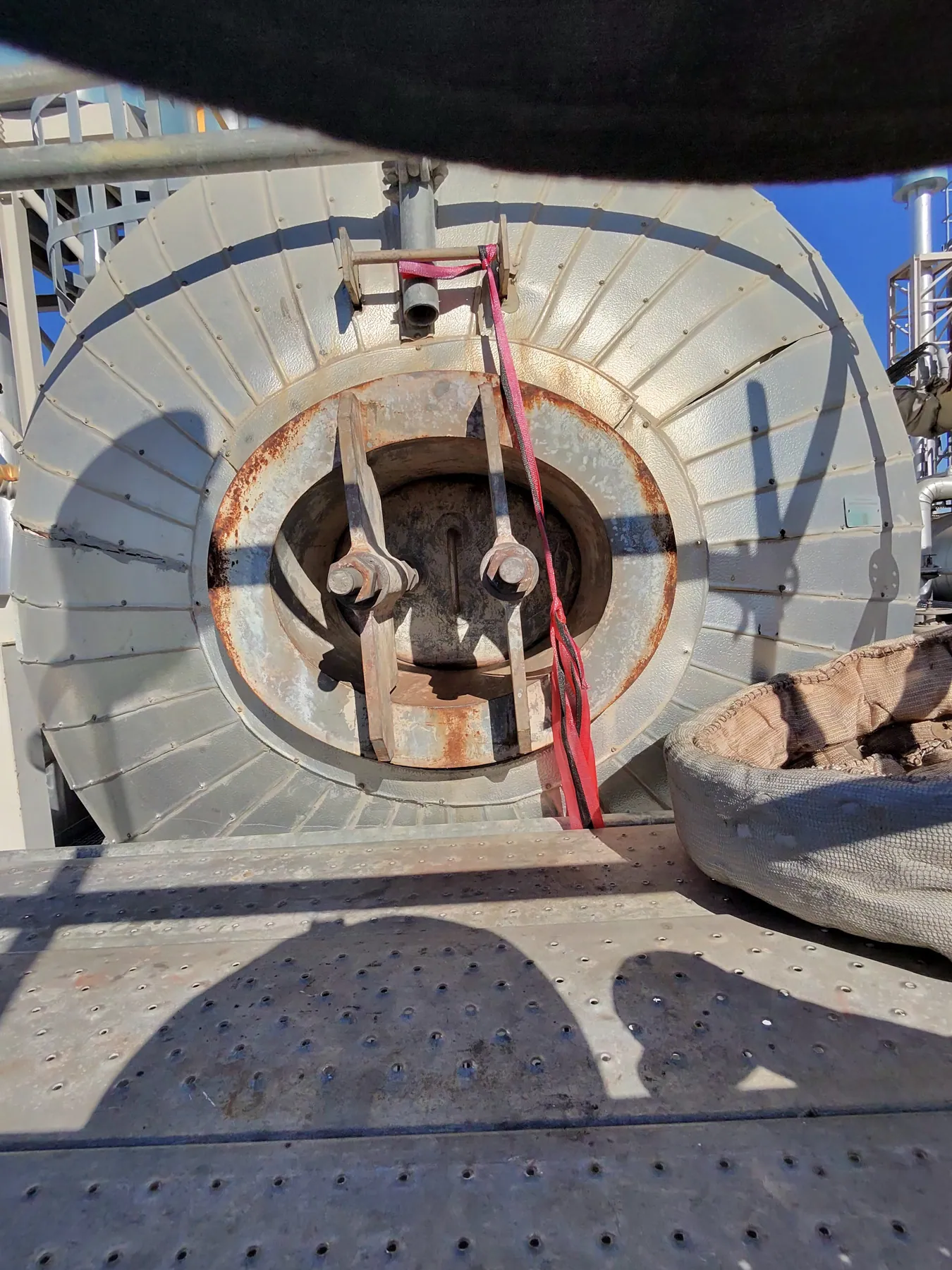 Open shaft hatch in a steel deck with rope line running into the space below