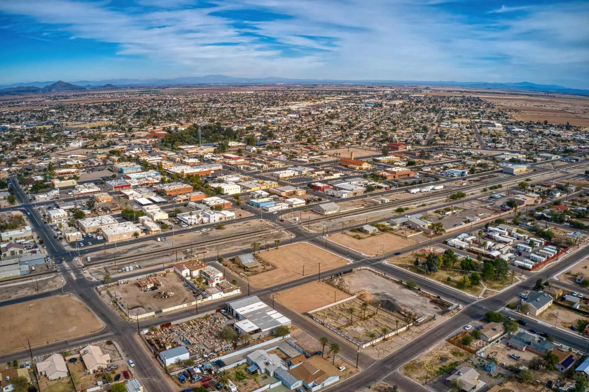 Wide aerial view of Casa Grande streets, rail lines, and surrounding farmland