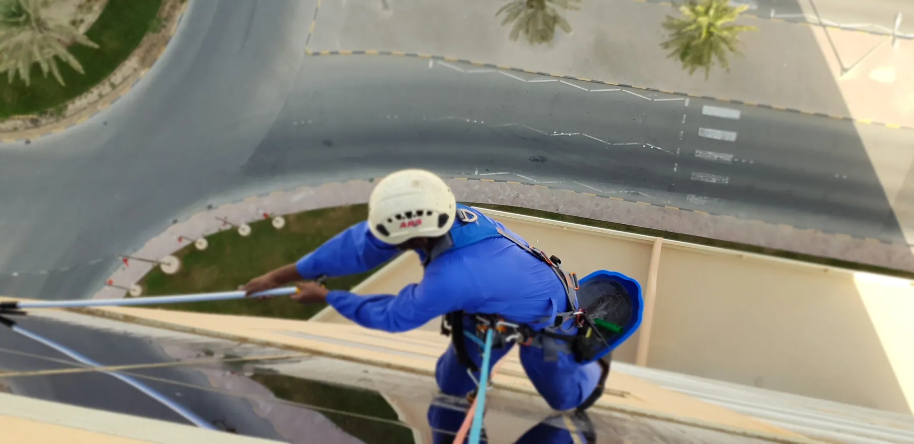 Rope access technician descending the curved facade of a tower on twin ropes
