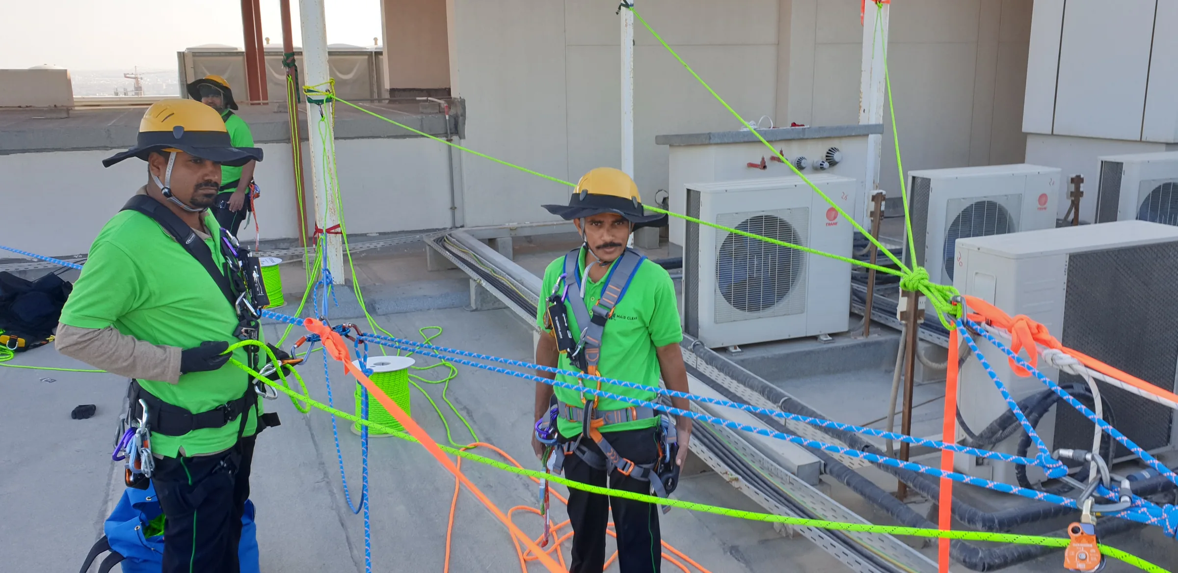 Harnessed technicians standing among color-coded rooftop rope systems