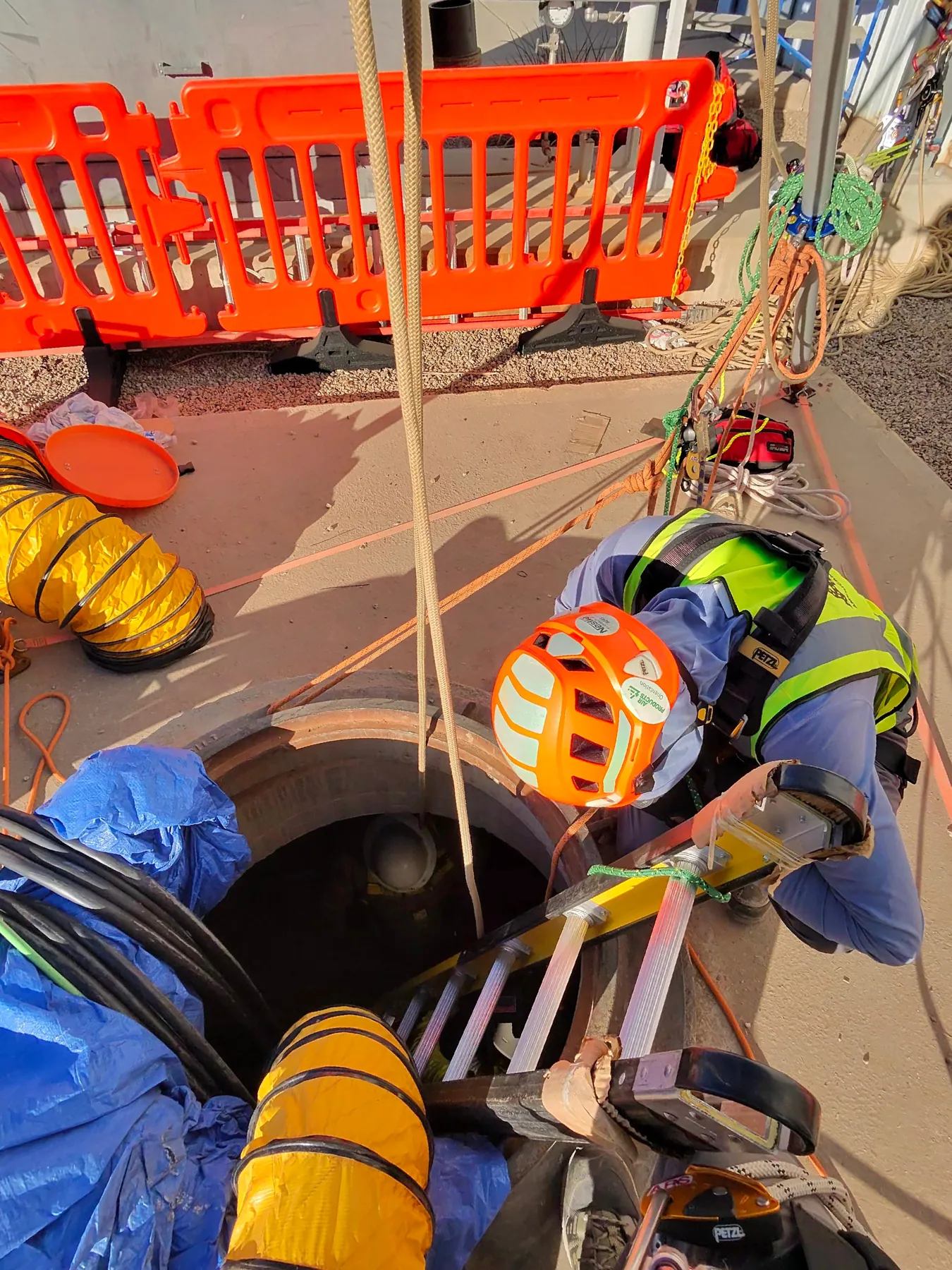 Overhead view of technicians working at a confined space entry point with rigged rope lines