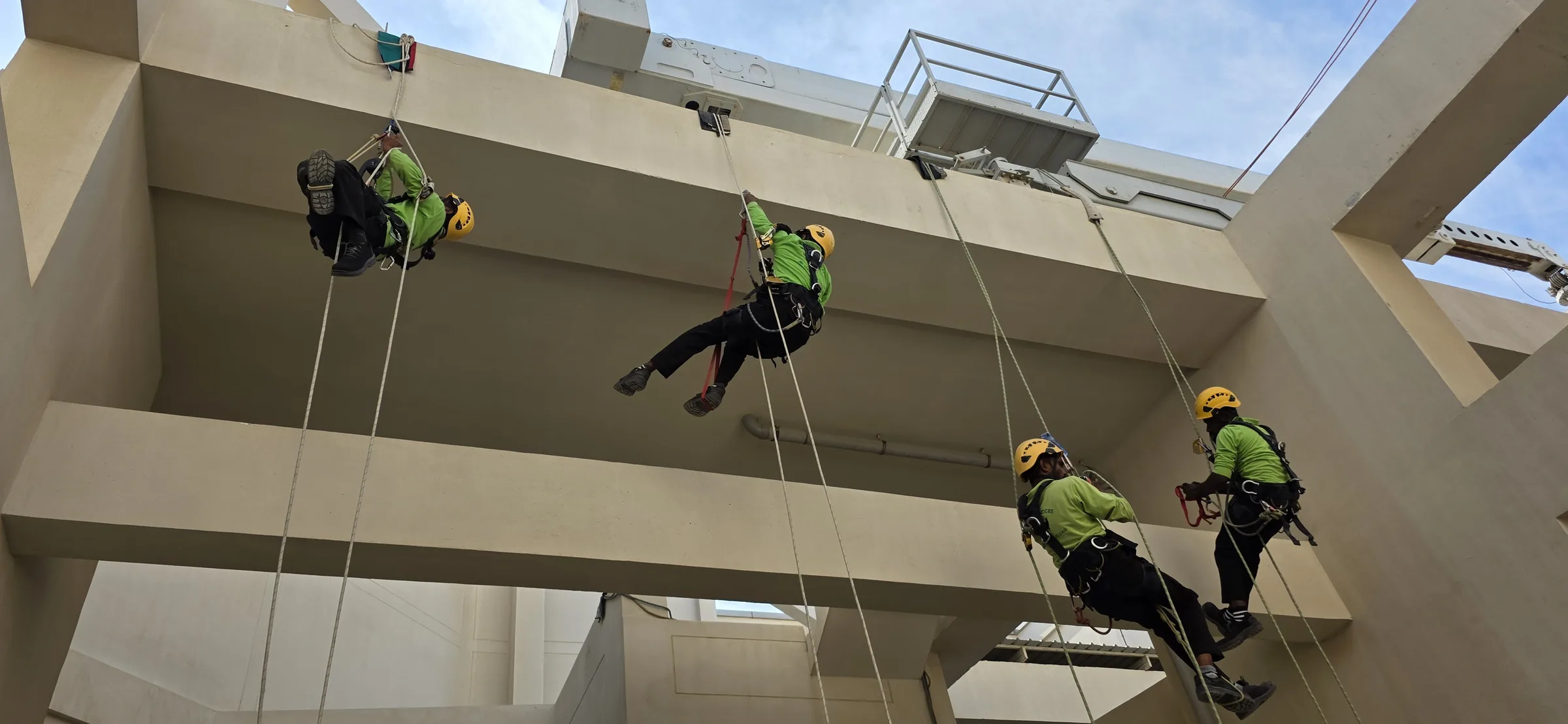 Technicians practicing controlled rope movement on a building facade